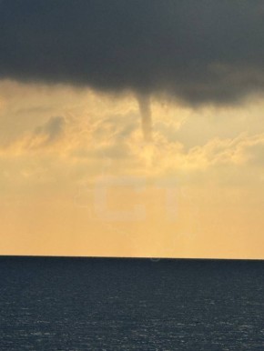 Тёмный смерч закрутился на фоне закатного неба